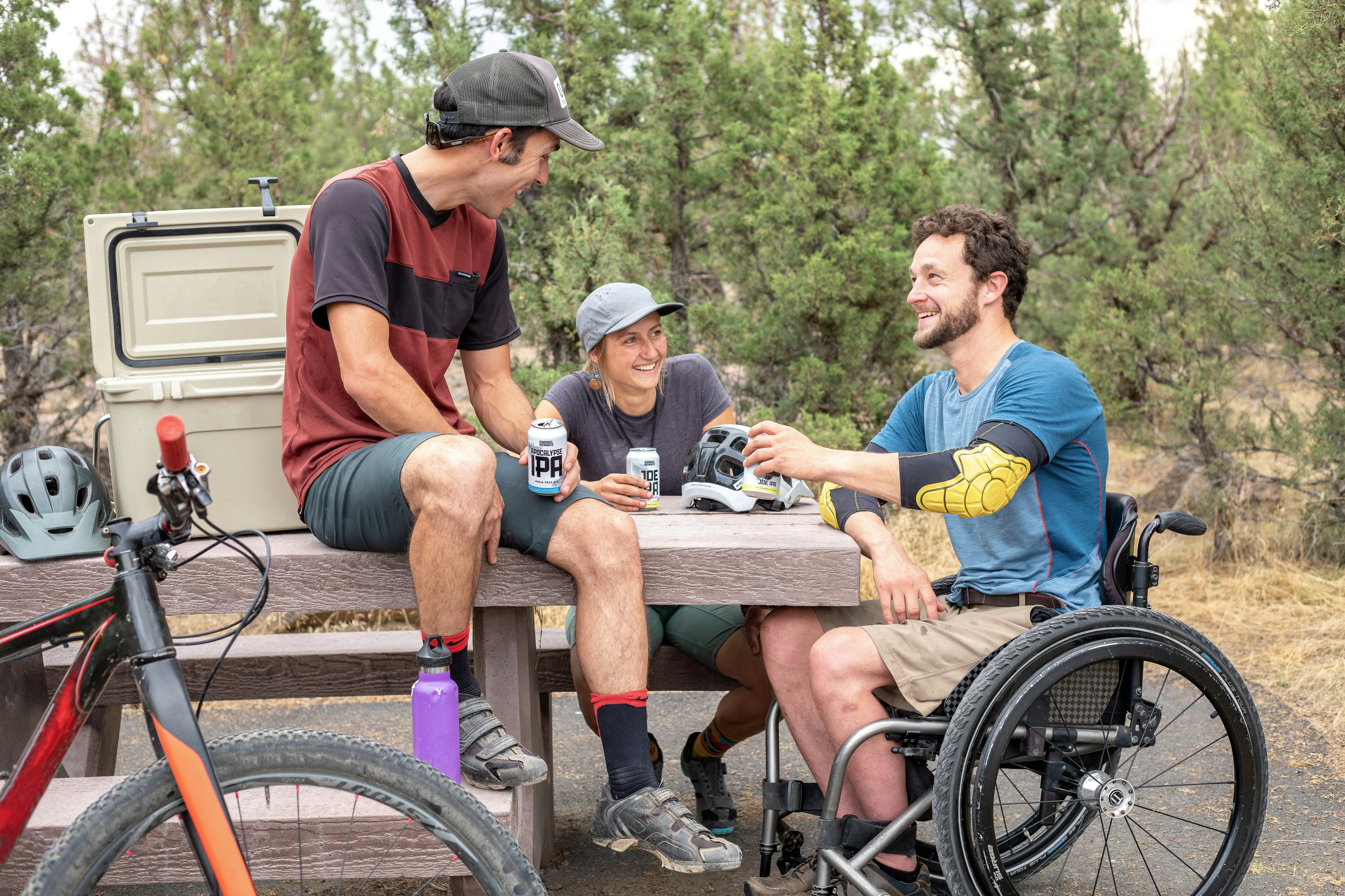 Friends enjoying the outdoors, including a person in a wheelchair with prosthetic limbs laughing with companions