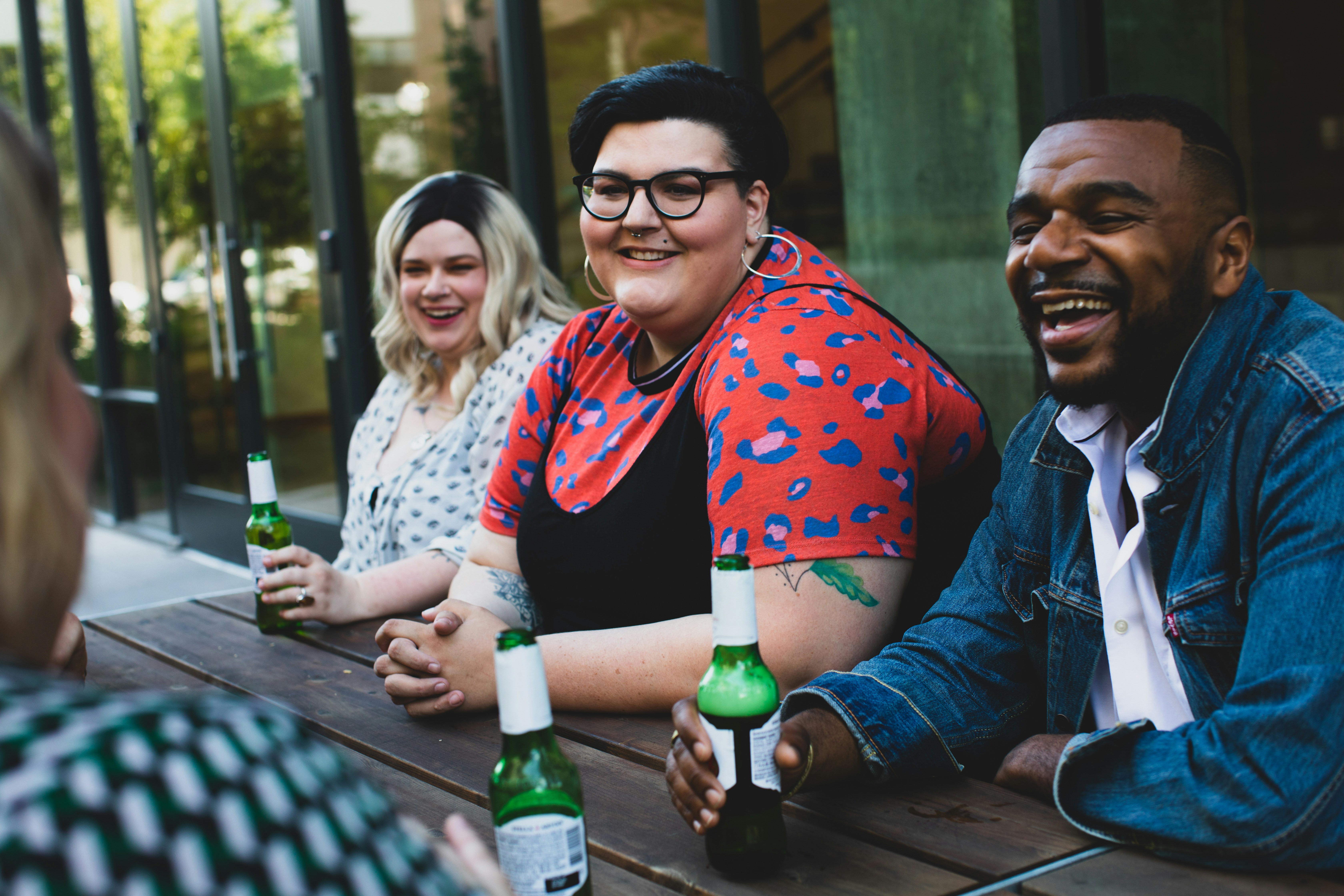 A diverse group of friends sitting together at an outdoor table, smiling and sharing drinks